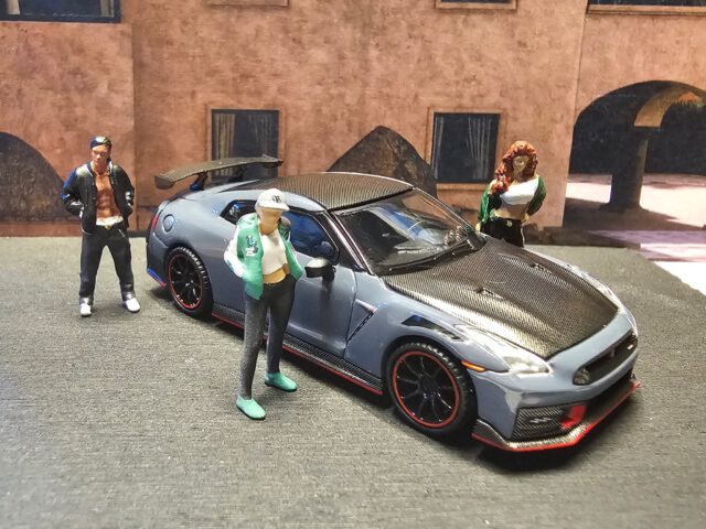 🥷 Stealth Mode: aktiviert.
Wenn ein GT-R leise aussieht, aber laut denkt, weißt du: NISMO ist im Raum. Stealth Gray, Carbon-Haut, rote Kanten wie Warnstreifen – und die Crew steht drum herum wie bei einem geheimen Midnight-Meet. Kein Smalltalk. Nur Respekt.
Specs & Vibes:
Hersteller: Mini GT (TSM Model)
Modell: Nissan GT-R NISMO 2024
Farbe: Stealth Gray
Look: Carbon-Optik auf Haube & Dach, NISMO-Redline, großer Wing, schwarze Wheels mit rotem Ring
Details: Detaillierte Headlights, sauberes Badging, scharfe Panel-Lines
Shot-Mood: Street-Diorama, leichtes Warmlicht – “built for attack” im Maßstab 1:64
Stealth außen. Sturm innen. NISMO macht keine Kompromisse.